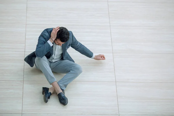 Frustrado joven empresario sentado en el suelo y mirando hacia abajo . — Foto de Stock