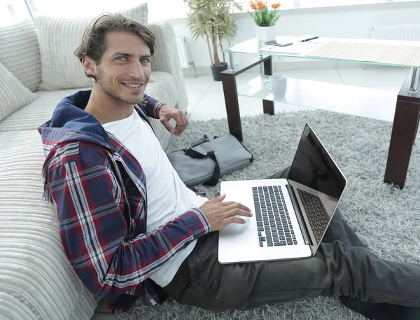 Biznes facet z laptopa siedząc na dywanie w salonie. — Zdjęcie stockowe