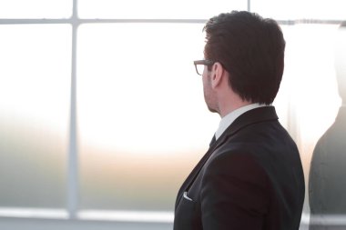 yan görünümü. ofis pencere duran işadamı.