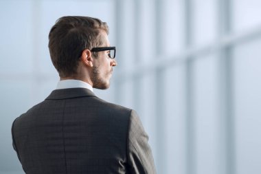 Ofis penceresinin yanında duran iş adamı.