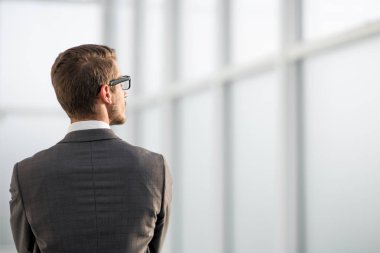 Ofis penceresinin yanında duran iş adamı.