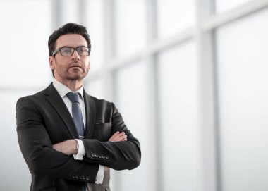 İş adamı pencerenin yanında duruyor ve ona bakıyor.