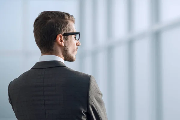 Πίσω όψη.επιχειρηματίας στέκεται κοντά στο παράθυρο του γραφείου — Φωτογραφία Αρχείου