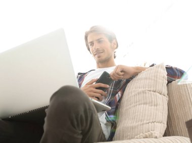 fotoğraf genç adam ile smartphone bir sandalyede oturuyor. bulanık bir arka plan üzerinde