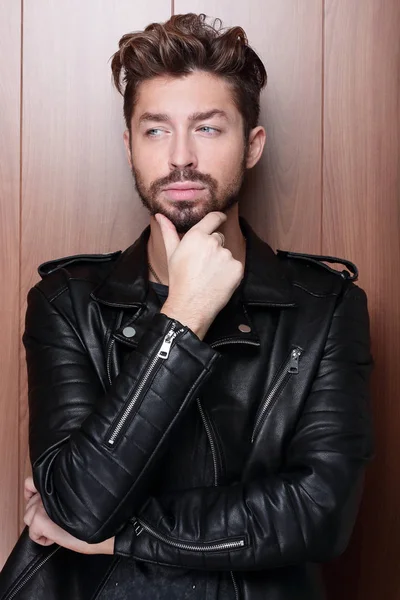 Siyah deri ceketli genç bir adamın portresi ahşap bir grunge kapıya karşı.