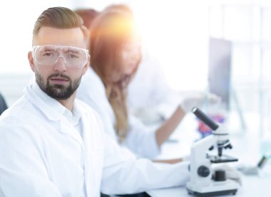 mikrobiyolog ve meslektaşları modern bir laboratuarda oturuyor