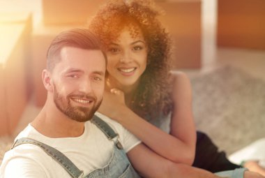 Genç bir çift yeni bir dairede yerde oturuyor.