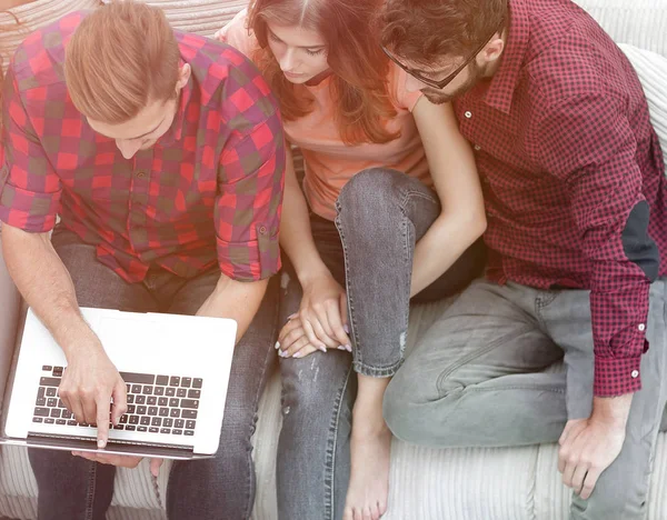Grupo de amigos com laptop sentado no sofá . — Fotografia de Stock
