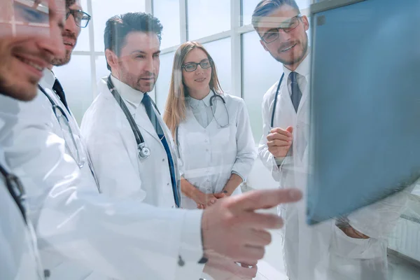 A través del vidrio. un grupo de médicos hablando de pie en la oficina — Foto de Stock
