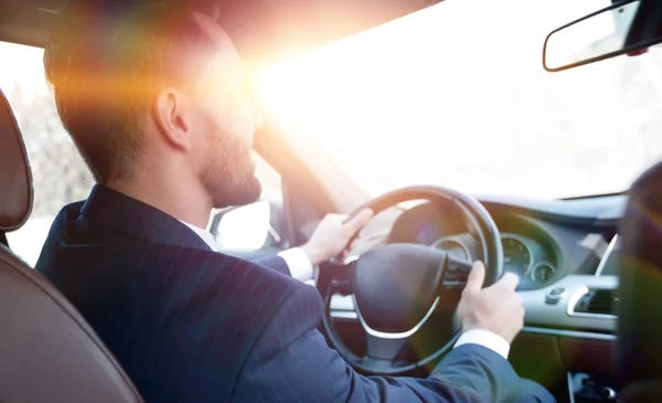 businessman sits at the wheel in his car and looks at the road