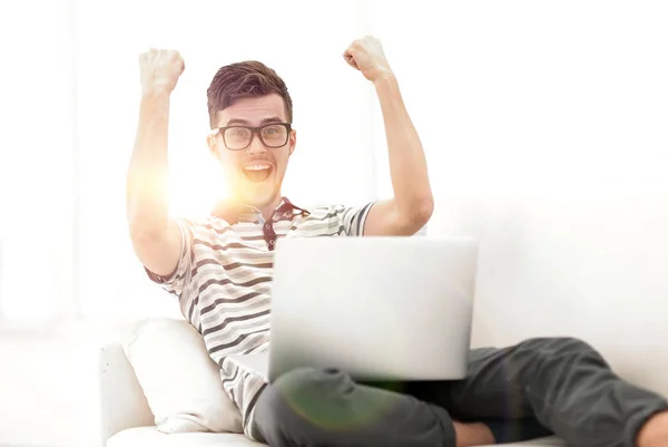 Hombre feliz con el ordenador portátil sentado en el sofá — Foto de Stock