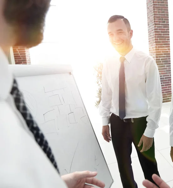 Empresário apontando equipe de negócios em um flipchart em branco . — Fotografia de Stock