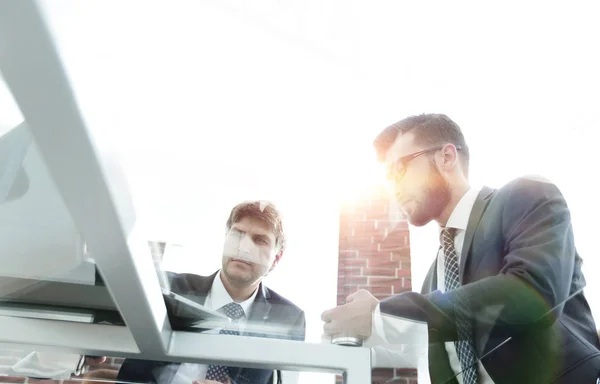 Blick von unten auf zwei Geschäftsleute, die an seinem Laptop arbeiten — Stockfoto