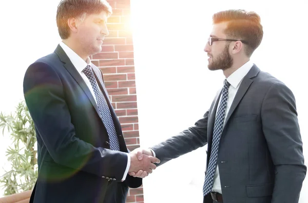 Businessmen shaking hands while standing in office corridor — Stock Photo, Image