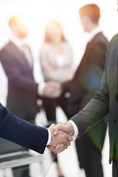 Två affärsmän skakar hand med kollegor på bakgrunden. — Stockfoto