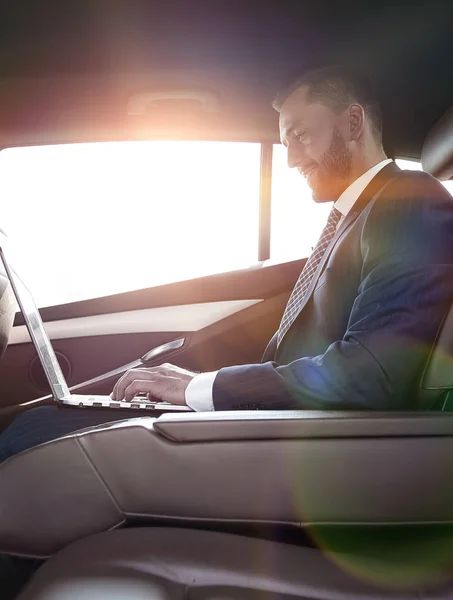 Hombre de negocios confiado sentado en el asiento trasero de un coche prestigioso — Foto de Stock