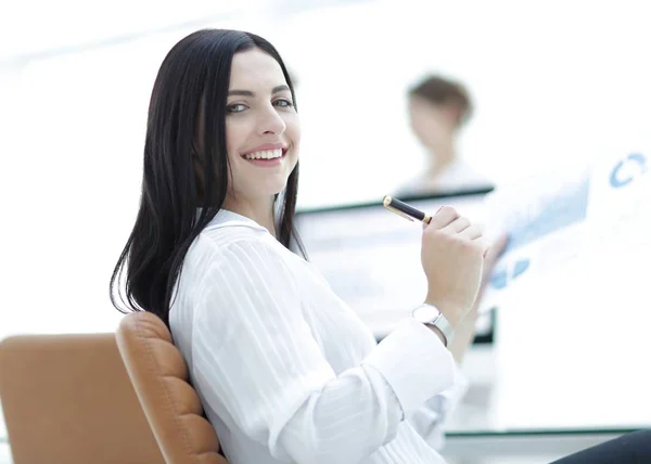 Uśmiecha się kobieta biznesu z dokumentów finansowych, siedząc na biurko. — Zdjęcie stockowe