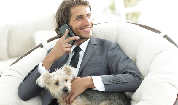 successful businessman holds his dog and pet and talks on the smartphone