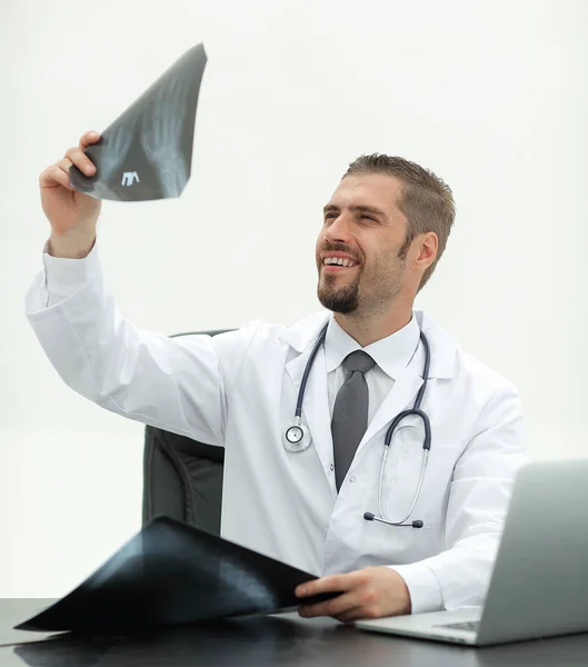 Arzt untersucht ein Röntgenbild, sitzt hinter einem Schreibtisch — Stockfoto