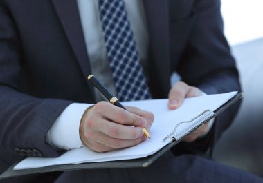 İşadamı bir sözleşme imzalar. Elinde kalem tutan.