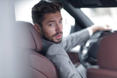 Başarılı bir adam prestijli bir arabanın direksiyonunda oturuyor.