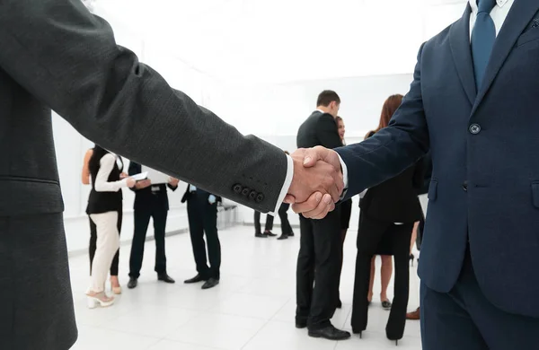 Крупним планом рукостискання ділових партнерів на фоні ділової команди — стокове фото