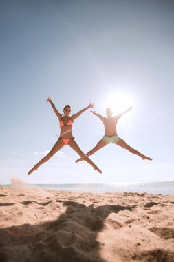 Kumsalda zıplayan mutlu bir çiftin fotoğrafı..