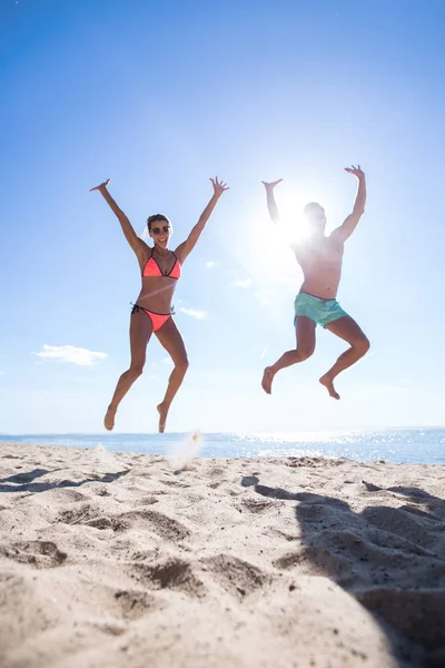 Glückliches Paar springt am Strand. — Stockfoto