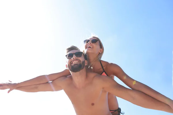 Mann trägt Frau huckepack am Strand. — Stockfoto