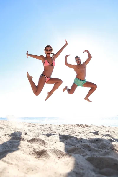 Pareja feliz saltando en la playa. — Foto de Stock