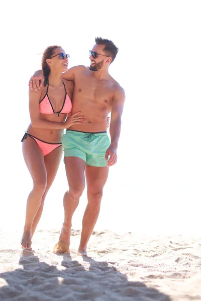 Unga par som håller händer och går på stranden. — Stockfoto