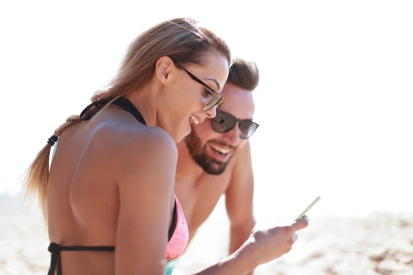 Lächelndes Paar beim Stöbern auf Fotos am Strand — Stockfoto