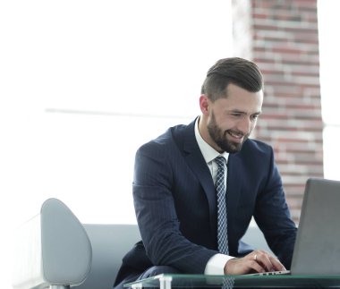 bir ofiste bir kanepede oturan dizüstü bilgisayar üzerinde çalışan iş adamı