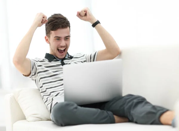 Homem feliz com laptop sentado no sofá — Fotografia de Stock