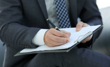 İşadamı bir sözleşme imzalar. Elinde kalem tutan.