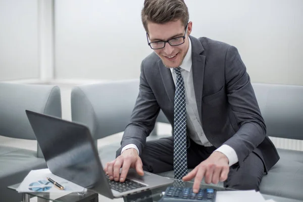 Cerrar up.smiling hombre de negocios utilizando el ordenador portátil y calculadora . — Foto de Stock