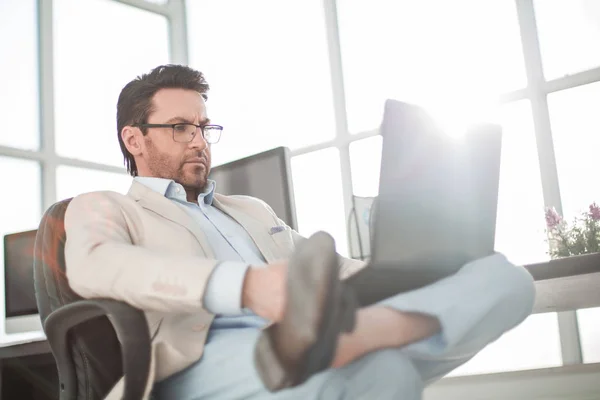 Empresário usando um laptop sentado em sua mesa — Fotografia de Stock