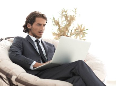 içinde büyük bir rahat armchai oturan dizüstü bilgisayar ile başarılı iş adamı