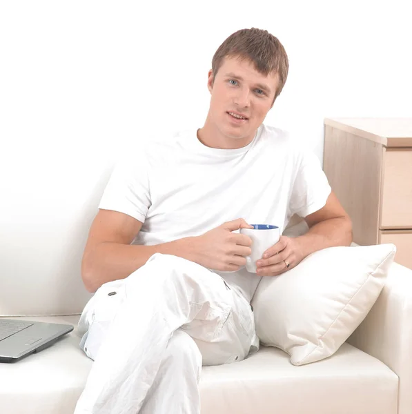 Příležitostné muž sedí na gauči doma s kávou. — Stock fotografie