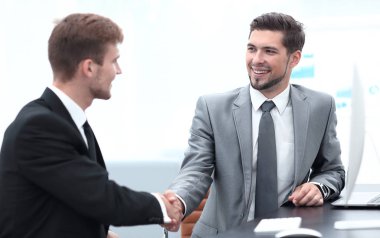 Masada oturan iş ortaklarının el sıkışması.