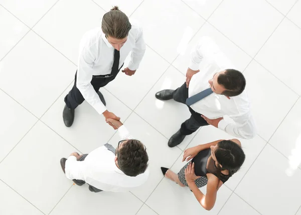 Uitzicht vanaf de top. collega's schudden handen in de lobby van het kantoor. — Stockfoto