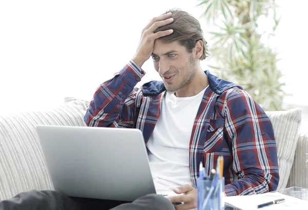 Glücklicher junger Mann, der von zu Hause aus mit Laptop arbeitet. — Stockfoto