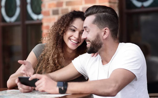 Happy älskande par som med en smartphone som sitter i terrass — Stockfoto