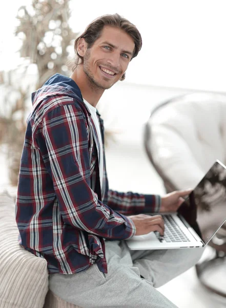 Stylowe młody człowiek pracuje na laptopie i patrząc na kamery — Zdjęcie stockowe