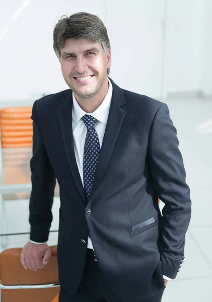 Hombre de negocios serio de pie cerca del lugar de trabajo en la oficina . —  Fotos de Stock