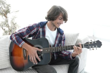 Yakışıklı adam evde kanepede gitar çalmaya