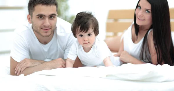 Retrato de familia joven y feliz acostados en la cama juntos —  Fotos de Stock