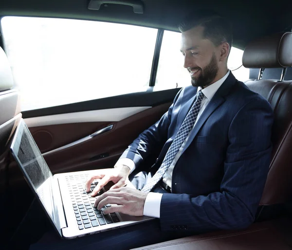 Uomo d'affari che lavora con il computer portatile seduto in auto — Foto Stock