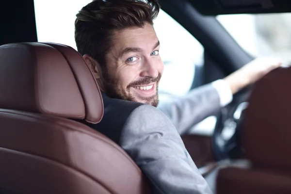 Vista posteriore, giovane che guida la sua auto, guardando la macchina fotografica — Foto Stock