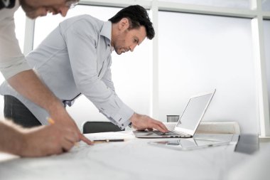 İki mimar çalışmak için bir dizüstü bilgisayar kullanır..